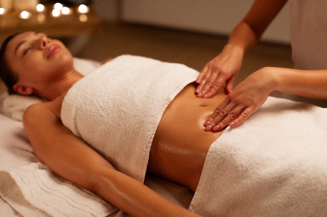 Professionelle Masseurin macht entspannende Massage des Bauches für Frau in ruhigen Spa-Center Interieur, Frau Arzt Masseur während der Arbeit mit Patienten